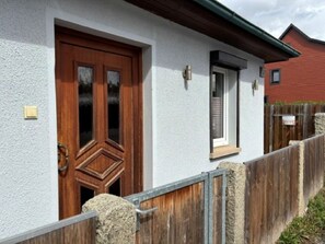 A house with a wooden door, a small window, and a wooden fence.