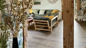 Un dormitorio tipo loft acogedor, con vigas de madera a la vista, estructura de cama de madera y una lámpara colgante.