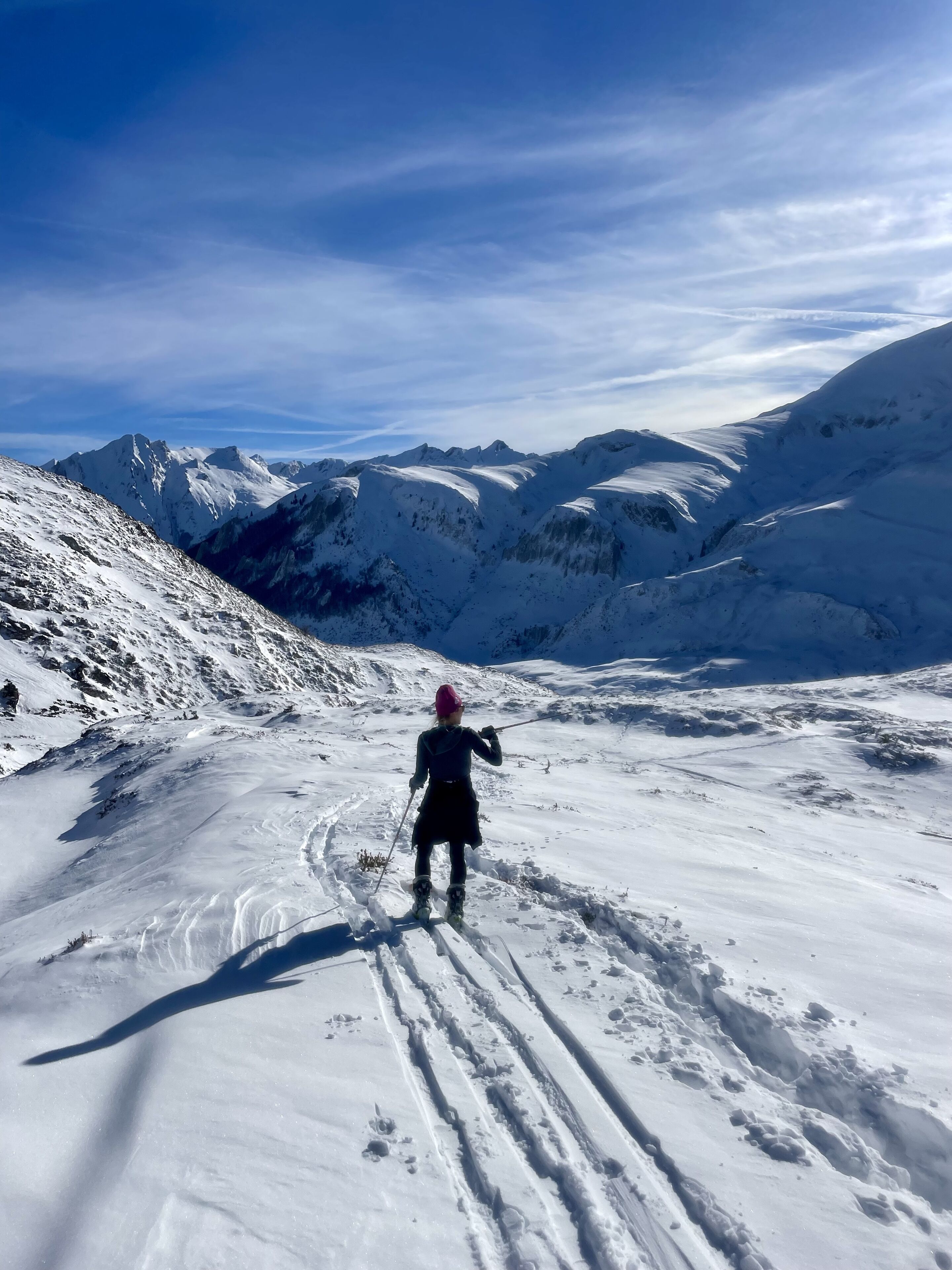 A person skiing down a snow-covered slope with a clear sky above.