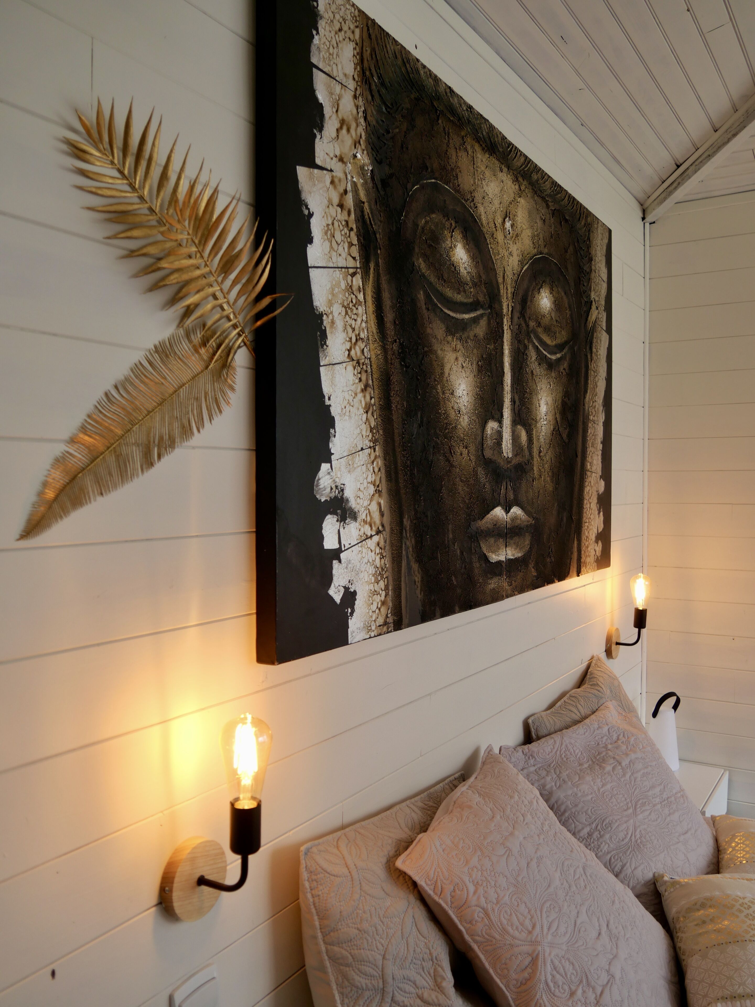 A bedroom with a bed, decorative wall art, and wall-mounted lighting.