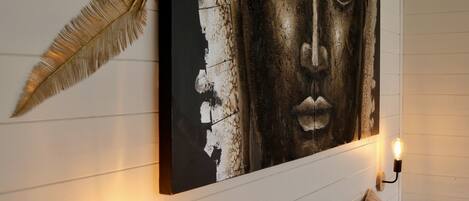 A bedroom with a bed, decorative wall art, and wall-mounted lighting.