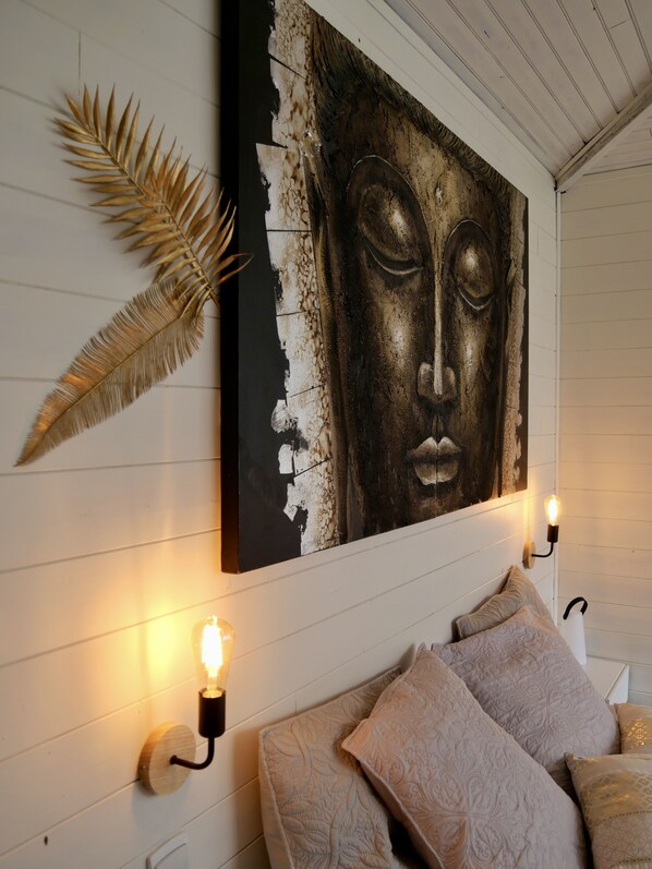 A bedroom with a bed, decorative wall art, and wall-mounted lighting.