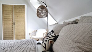 Ein Schlafzimmer mit einem großen Bett, einem Korbstuhl und einem Deckenventilator.