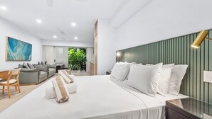 A modern hotel room with a large bed, a desk, and a sofa.