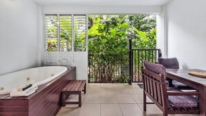 A bathroom with a bathtub, wooden bench, and a table with chairs.