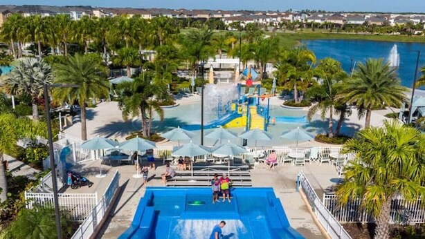 Ein Wasserpark mit großem Pool, Rutschen und Palmen.