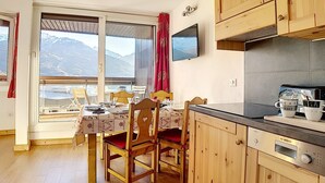 Una cocina acogedora con armarios de madera, una cafetera Bosch y un comedor con una mesa lista para dos.