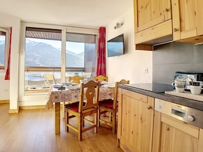 A cozy kitchen with wooden cabinets, a Bosch coffee maker, and a dining area with a table set for two.
