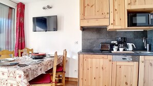 Una cocina compacta con armarios de madera, un microondas, un tostador y una cafetera.