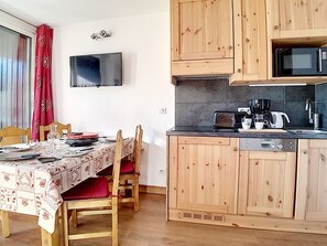 A compact kitchen with wooden cabinets, a microwave, a toaster, and a coffee maker.