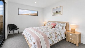 A bedroom with a bed, bedside tables, a chair, and a window. - The Bay View San Remo by Ready Set Stay (San Remo)