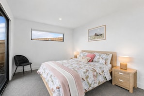 A bedroom with a bed, bedside tables, a chair, and a window. - The Bay View San Remo by Ready Set Stay (San Remo)