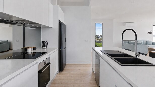 A modern kitchen with a black refrigerator, stainless steel appliances, and a view to the outside. - The Bay View San Remo by Ready Set Stay (San Remo)