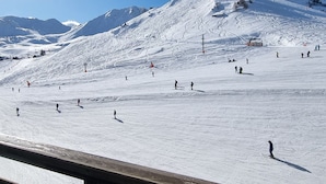 Pista de esquí cubierta de nieve con esquiadores y una baranda de madera al frente.