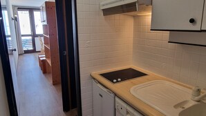 Una cocina con baldosas blancas, encimera de madera y lavavajillas.