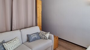 Salón en tonos neutros con un sofá, dos cojines estampados y un detalle de madera.