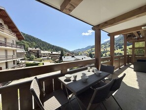 Un balcon agrémenté de meubles en osier, une table avec des tasses et une vue sur un paysage montagneux.