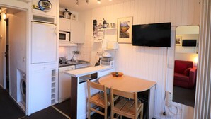 A compact kitchen with a microwave, sink, and a small dining area with a table and chairs. - Comfortable studio with balcony, pets allowed, near slopes (Tignes)
