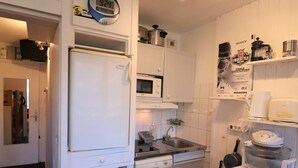 A compact kitchen with white appliances, a microwave, a sink, and a coffee maker. - Comfortable studio with balcony, pets allowed, near slopes (Tignes)