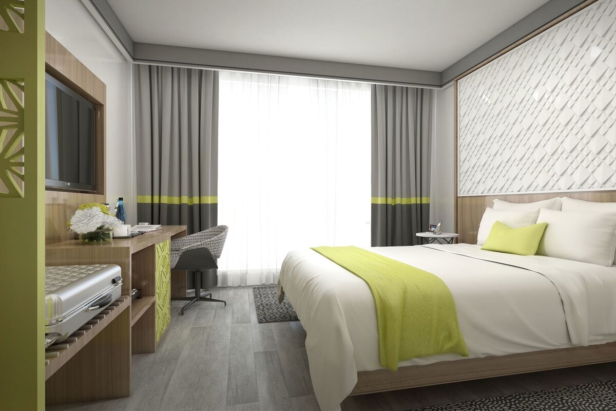 Une chambre d’hôtel moderne équipée d’un lit, d’un bureau, d’une chaise et d’un téléviseur.