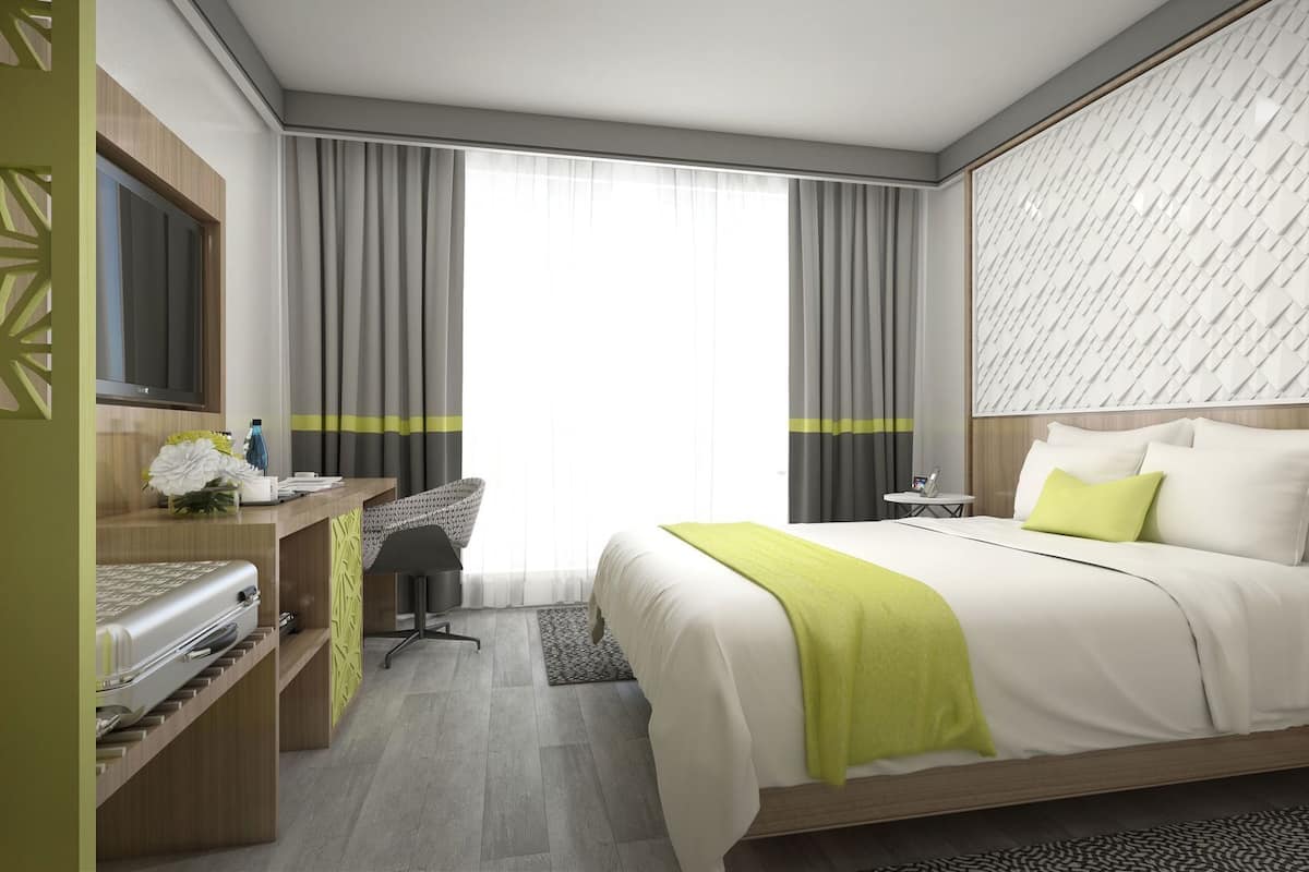 Une chambre d’hôtel moderne équipée d’un lit, d’un bureau, d’une chaise et d’un téléviseur.