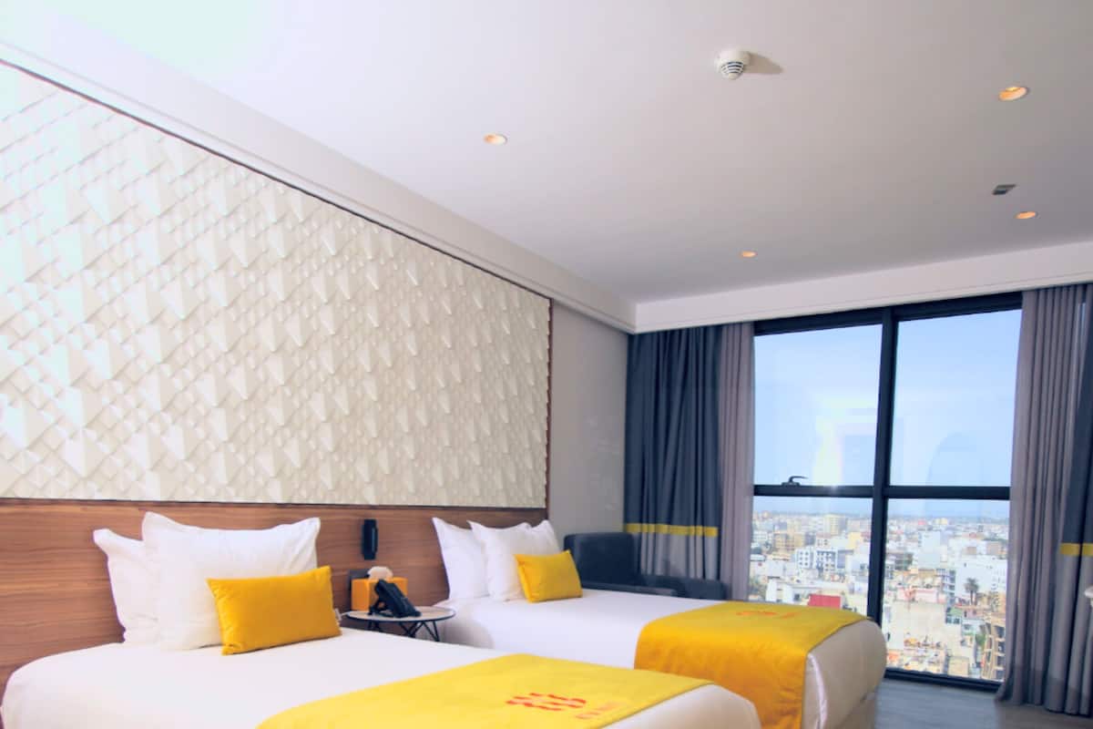 Une chambre d’hôtel avec deux lits, une vue sur la ville et un design moderne.