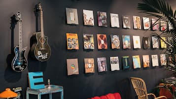 A wall with various music album covers and a guitar.
