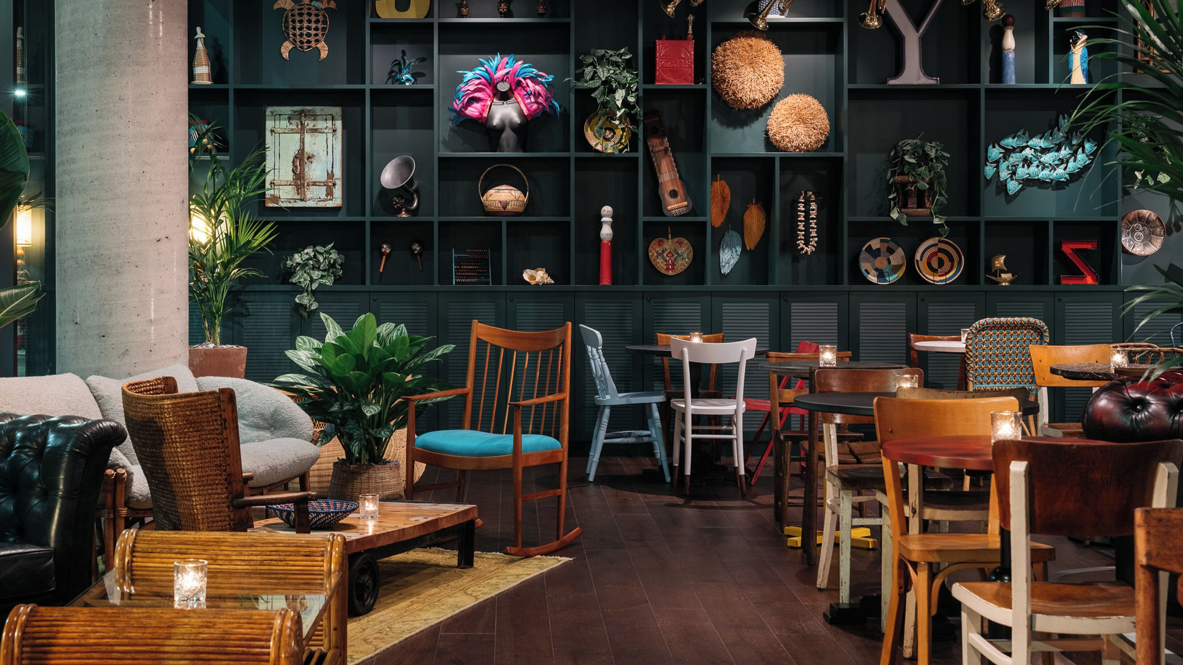 A cozy interior with a sofa, chairs, a dining table, and a bookshelf filled with decorative items.