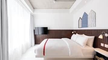 A modern hotel room with a bed, bedside lamps, a TV, and a wall-mounted artwork.
