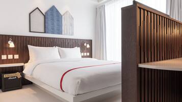 A modern hotel room with a wooden headboard, a white bed with red accents, a Marshall amplifier, and wall-mounted sconces.