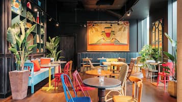 Interior de un restaurante con cabinas, mesas, sillas y plantas en macetas.