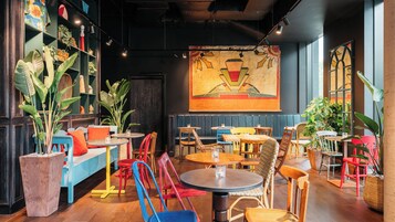 A restaurant interior with booths, tables, chairs, and potted plants.