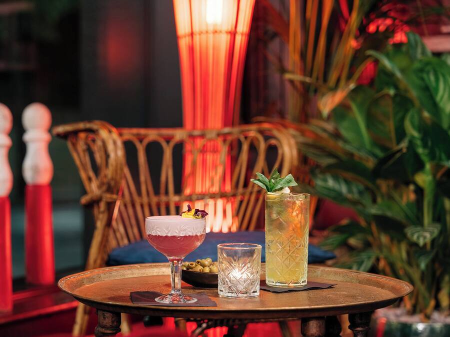 A table with a cocktail glass, a glass of water, and a tall glass with a drink.