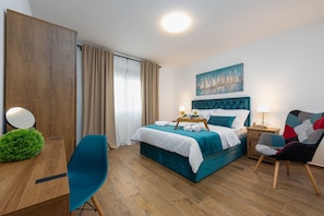 A hotel room with a bed, a desk, a chair, a nightstand, and a painting on the wall. - Villa Roza (Policnik)
