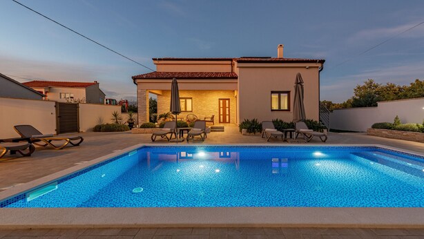 Une piscine avec des chaises longues et une maison en arrière-plan.