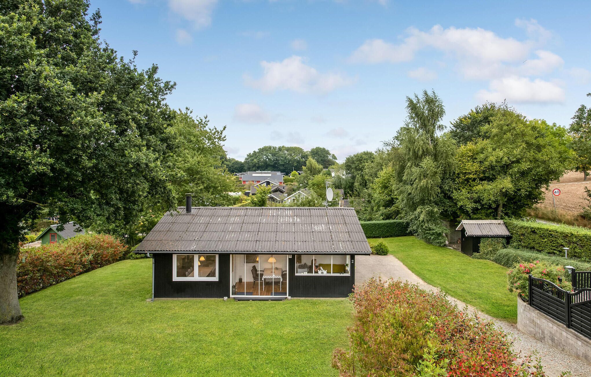 Een modern huis met een donkere gevel, grote ramen en een verzorgd gazon.