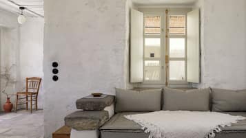 Une pièce comprenant un lit, une chaise, une fenêtre et un luminaire fixé au mur.