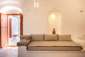 A room with a bed, a door, and a wall-mounted light fixture. - Santa Irini Retreat (Therasia)