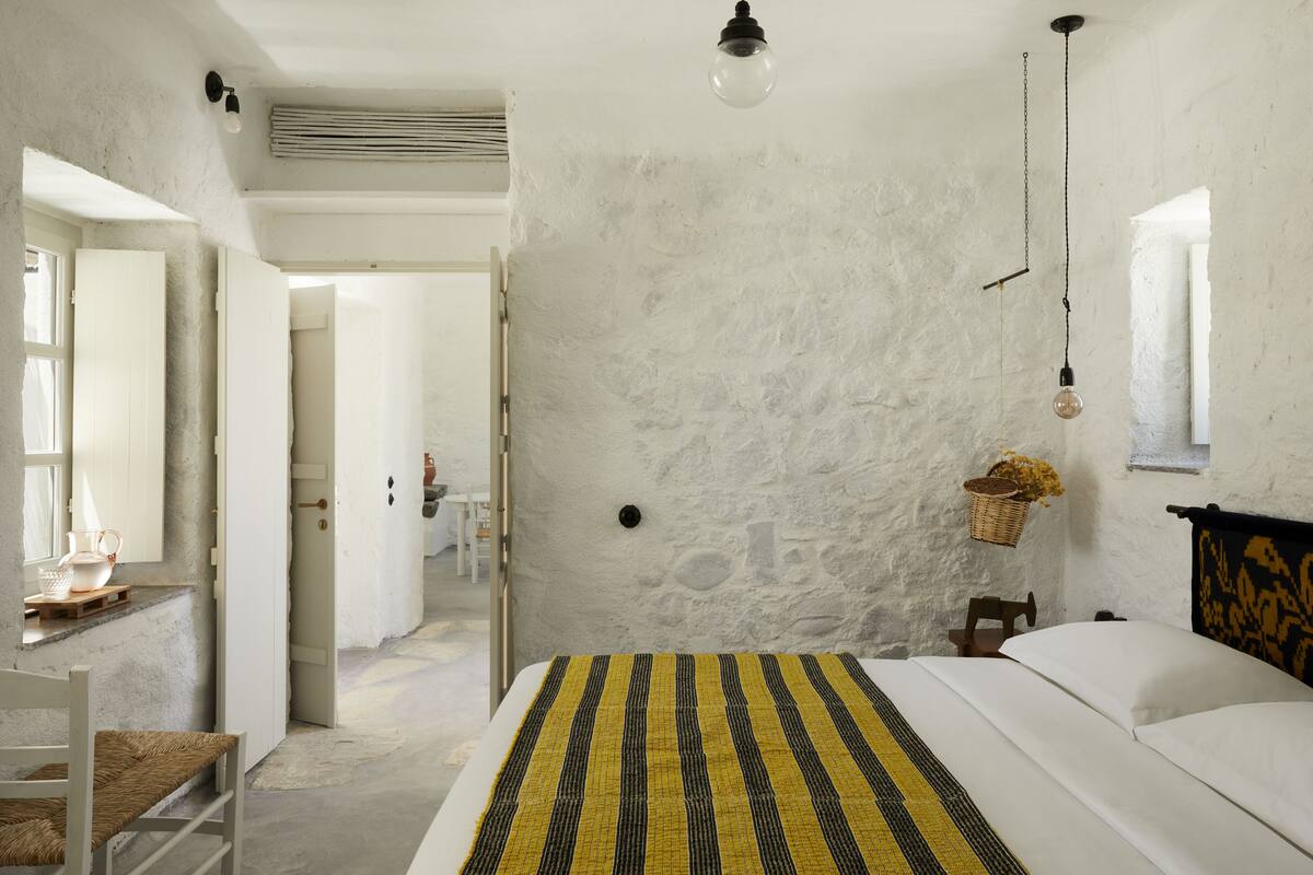 A bedroom with a bed, a chair, a desk, and a window.