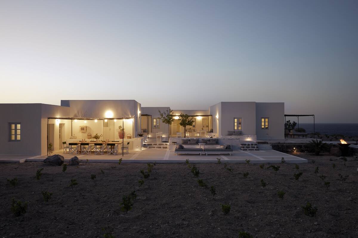A modern house with a dining area, outdoor seating, and a view of the sea.