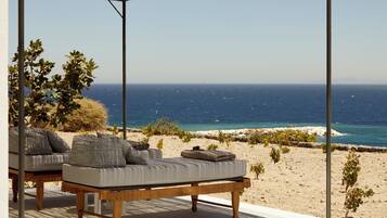Un salon de plage avec vue sur la mer, comprenant une table en bois et des coussins à rayures.