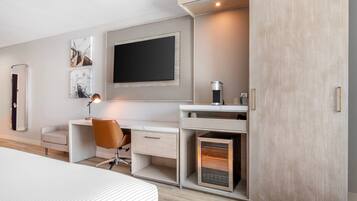 A modern bedroom with a bed, a desk with a chair, a TV, and a wardrobe.