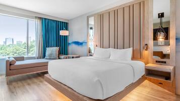 Een moderne hotelkamer met een groot bed, een zithoek, een groot raam met uitzicht op de stad en een houten accentmuur.