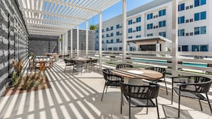 A rooftop terrace with outdoor seating, a pool, and modern buildings in the background. - Cambria Hotel Waco Univ Riverfront (Waco)