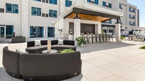 A modern hotel exterior with a covered outdoor seating area, large windows, and a clean, contemporary design. - Cambria Hotel Waco Univ Riverfront (Waco)
