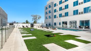 Une cour d’hôtel moderne dotée d’une piscine, de chaises longues et d’une pelouse bien entretenue.