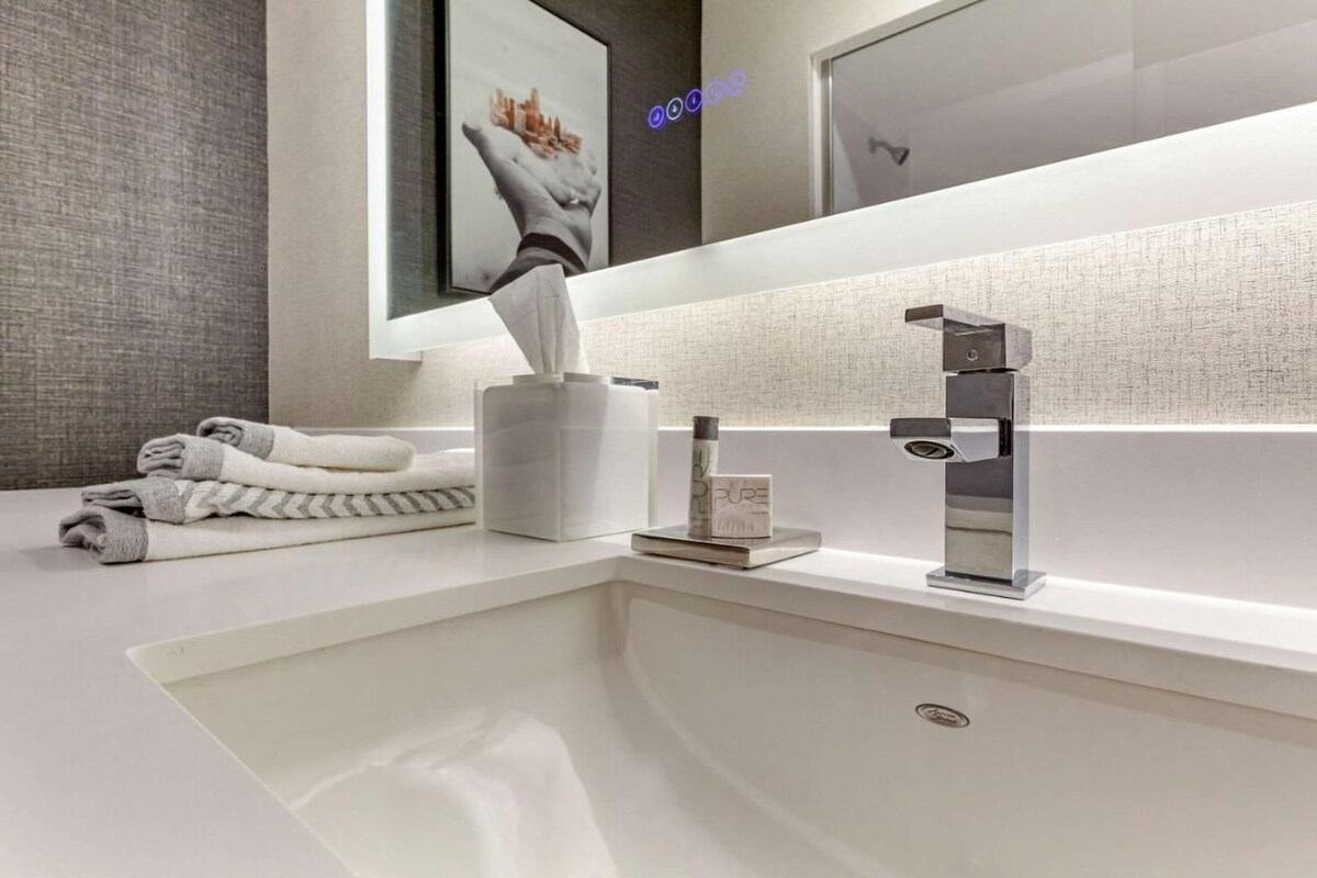 A modern bathroom with a white sink, a towel rack, a tissue dispenser, and a mirror.