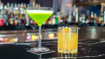 A bar with a martini glass and a highball glass on a marble surface.