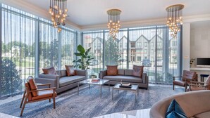 A spacious living room with large windows, a modern chandelier, and a comfortable seating area. - Cambria Hotel Waco Univ Riverfront (Waco)