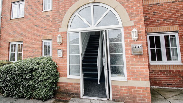 A brick building with a large arched entrance, a staircase leading inside, and a well-maintained hedge in front. - Sandall Apartment (Doncaster)